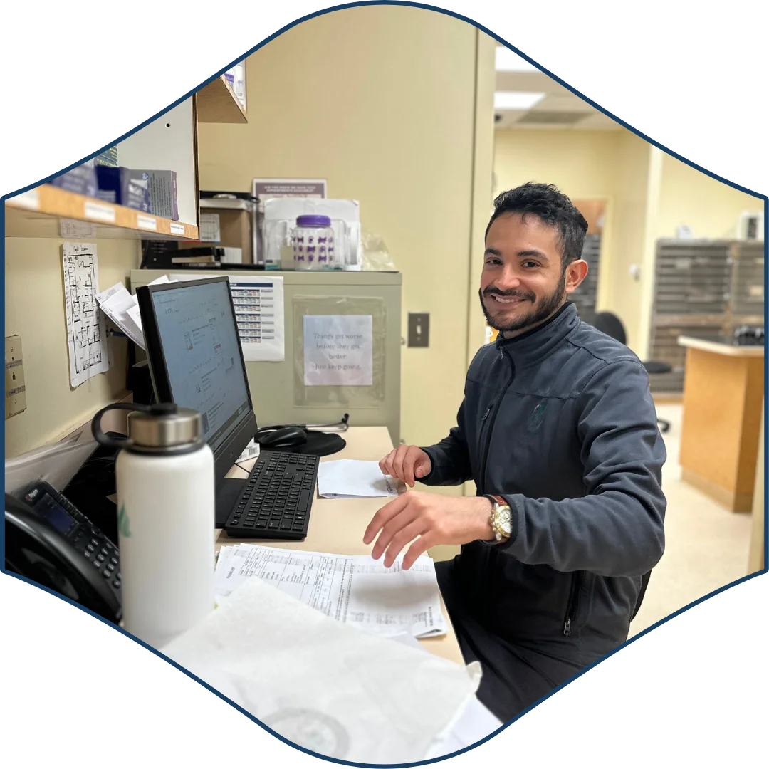 Smiling team member seated at a desk with a computer and paperwork inside the veterinary clinic.